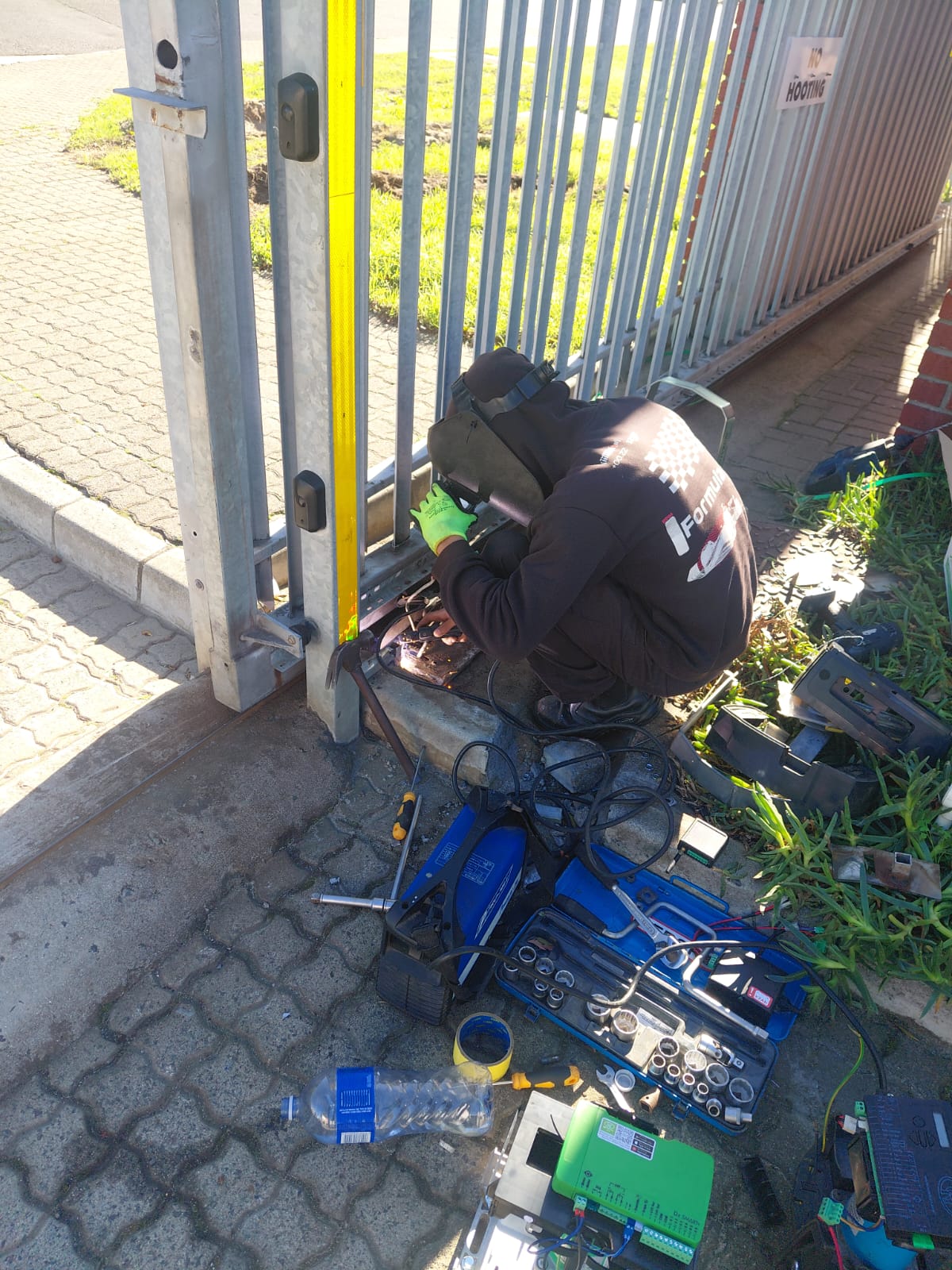 Close-up of a technician welding and fitting a gate automation motor